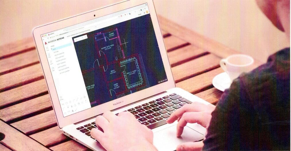 A person using a laptop on top of a wooden table.