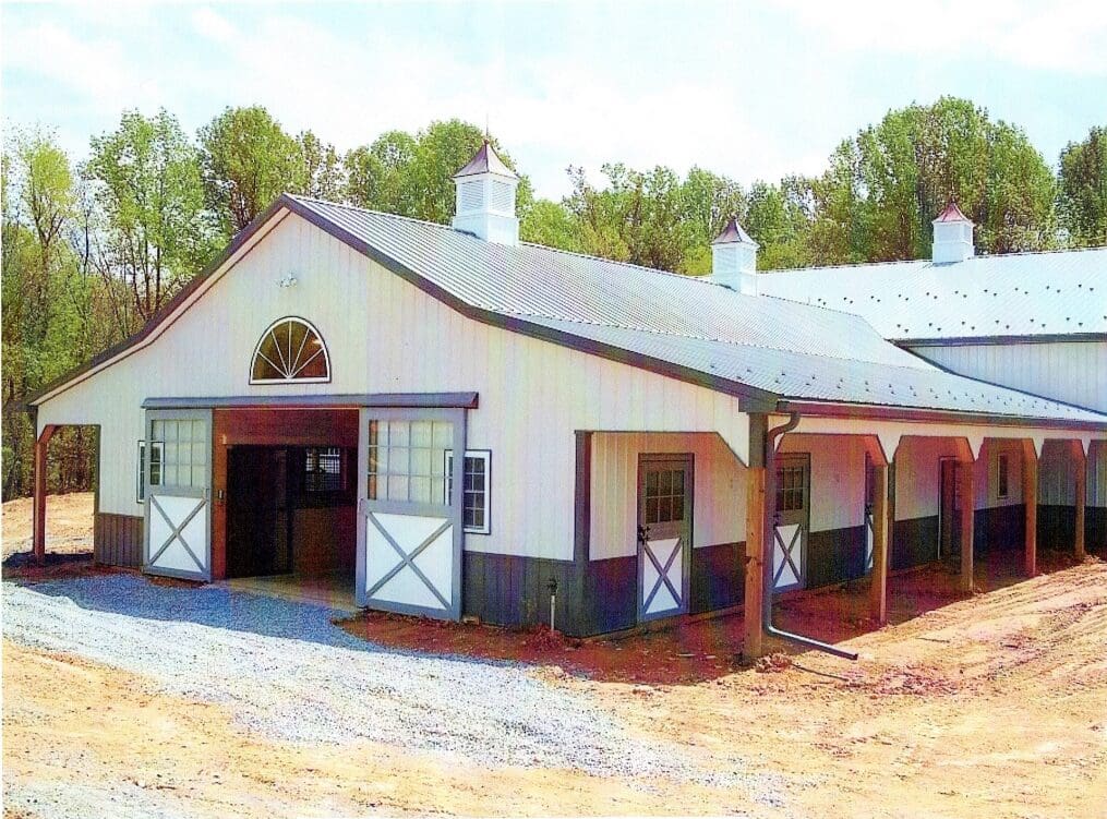 A white barn with two stalls and a porch.