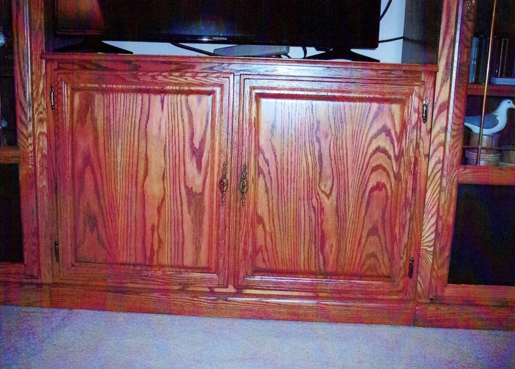 A red wooden cabinet with two doors and a black handle.