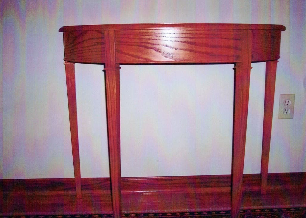 A wooden table with two legs and one of the legs is bent.