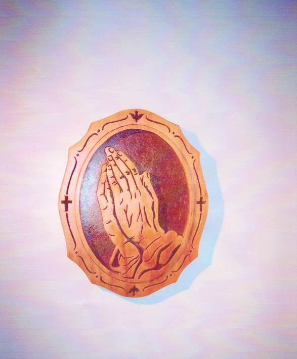 A wooden frame with a praying hands on it.